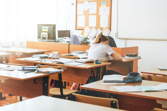 Eine junge Frau sitzt alleine in einem Klassenzimmer